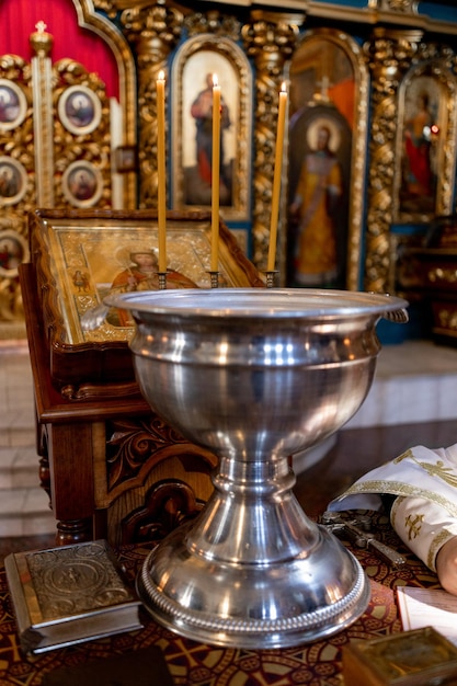 Metal font for christening in the church with candles