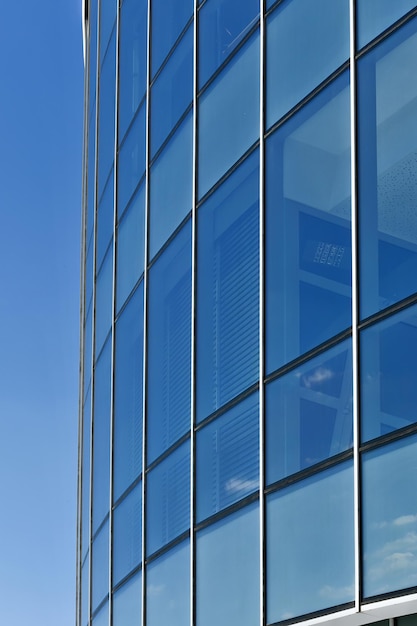 Metal glass part of the building against the blue sky as an abstract industrial background