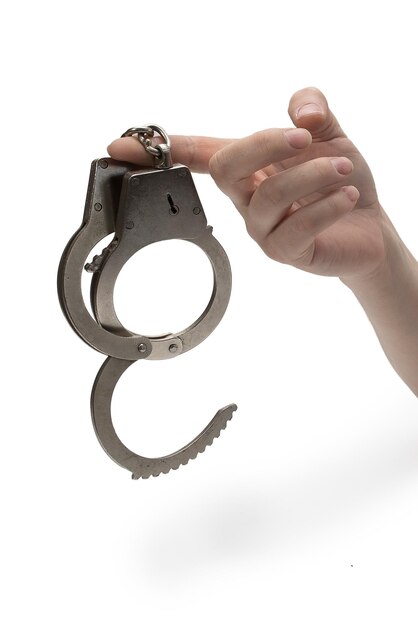 Metal handcuffs with a chain on a light background in a female hand