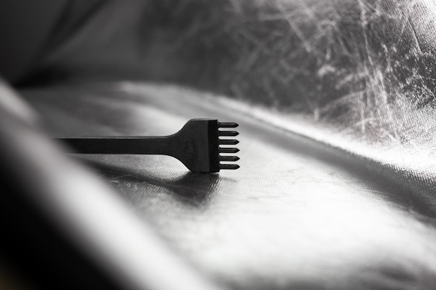 Metal iron tool, detail, lies on a silver background