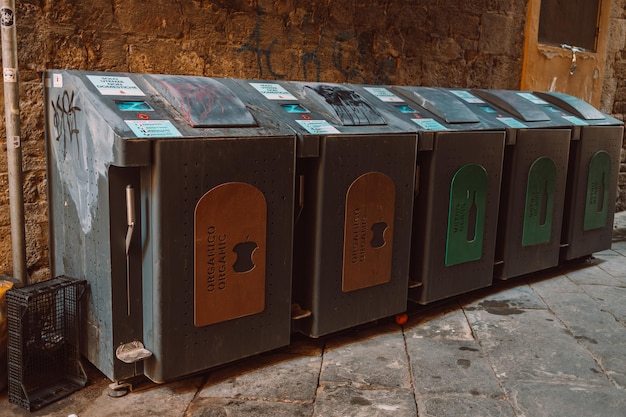 Metal iron trash bins sit on cement driveway beside the house in front of brown bricks wall as background Each separate kind of junk ex