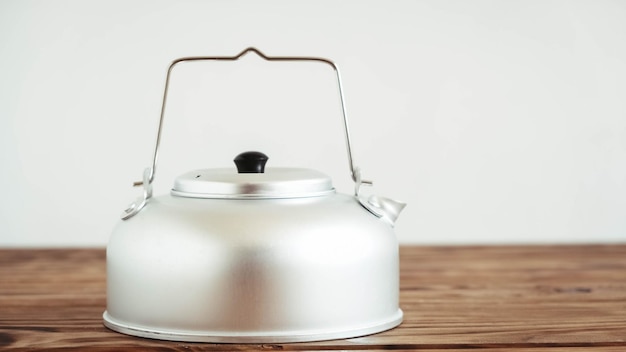 Metal kettle for hiking on a wooden table background