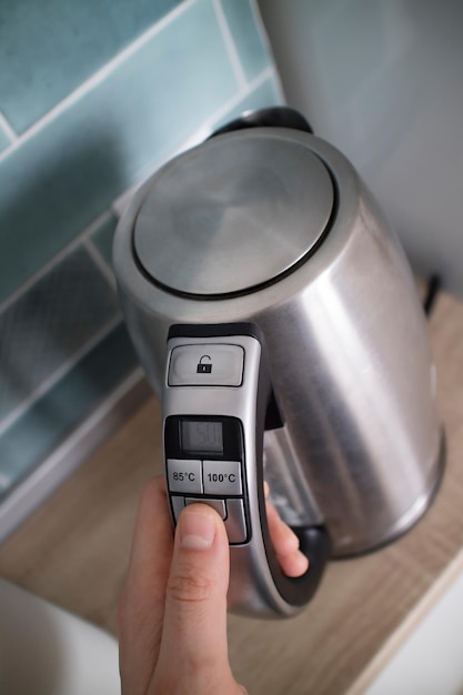 Metal kettle in the kitchen in the man hand on a kitchen