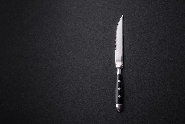 Metal kitchen knife on a dark textured concrete background