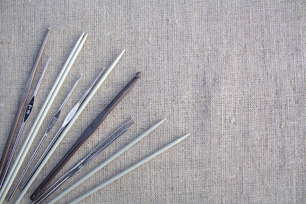 Metal knitting needles and hooks on a linen tablecloth. The concept of needlework, hobby.