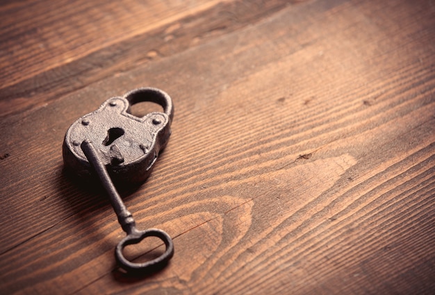 Metal lock and key on wooden table