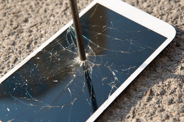 Metal nail and smartphone with a broken screen over the stone surface The concept of strength