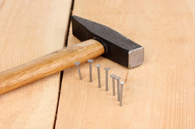 Metal nails in wooden plank and hammer