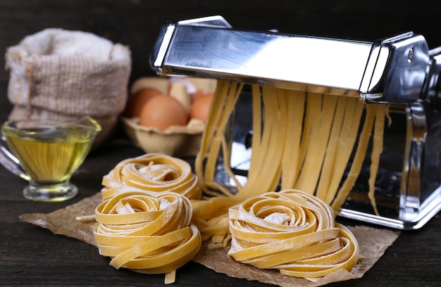 Metal pasta maker machine and ingredients for pasta on wooden table