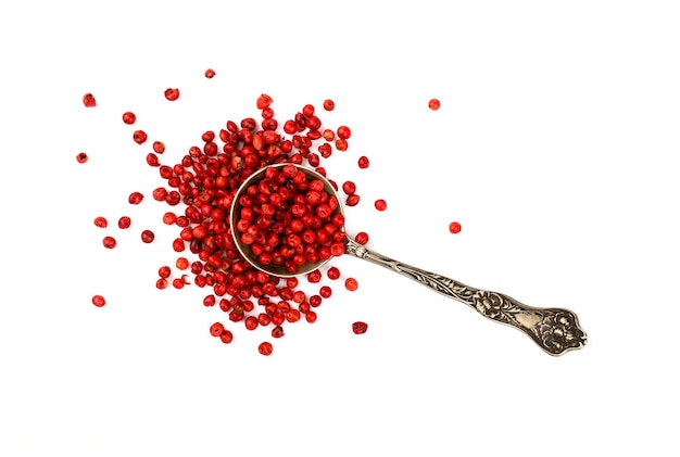 Metal spoon full of pink peppercorns