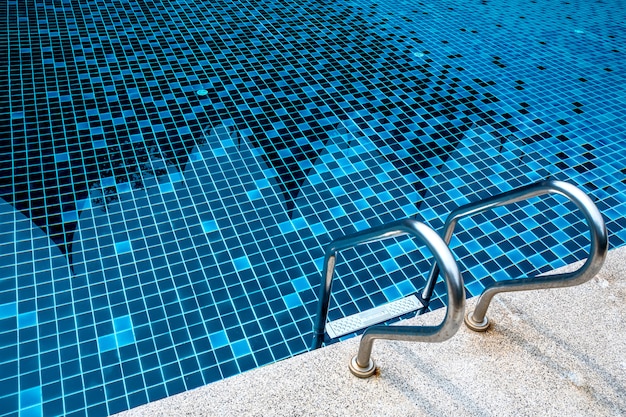 Metal stainless steel ladder in summer blue swimming pool