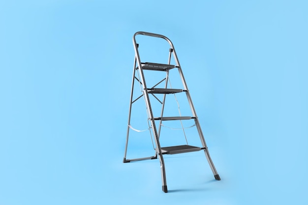 Metal stepladder on light blue background Construction equipment