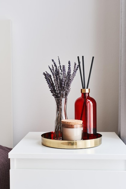 Metal tray with dried lavender aroma candle and room fragrance diffuser on a bedside table