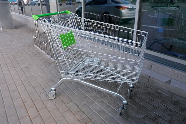 Metal trolley on wheels for purchases of goods in a supermarket near the entrance to the store, close-up