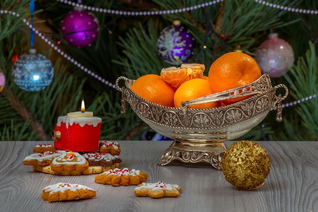 Metal vase with oranges and fir tree with toy balls on the background