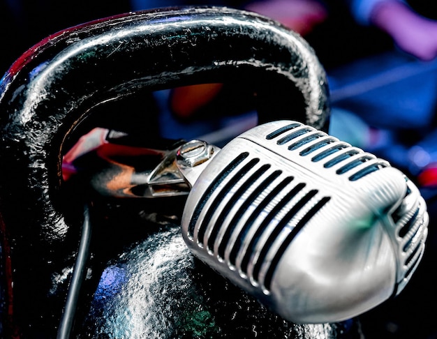 Metal vintage microphone lies on a black sports kettlebell in the institution. High quality photo