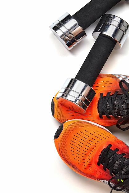 Metallic heavy dumbbell dropped on leg in orange sneaker isolated on white background