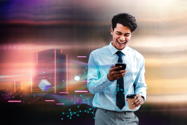 Metaverse and Blockchain Technology Concept. Cheerful Young Asian Businessman Enjoying Metaverse Virtual World via Mobile Phone in the City. Futuristic Tone