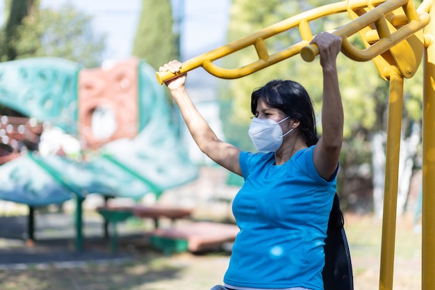 Mexican aged woman training on a playground wearing face mask due to pandemic