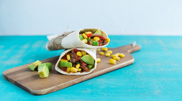 Mexican burritos on a kitchen table on a blue background. Mexican cuisine concept. Copy space.