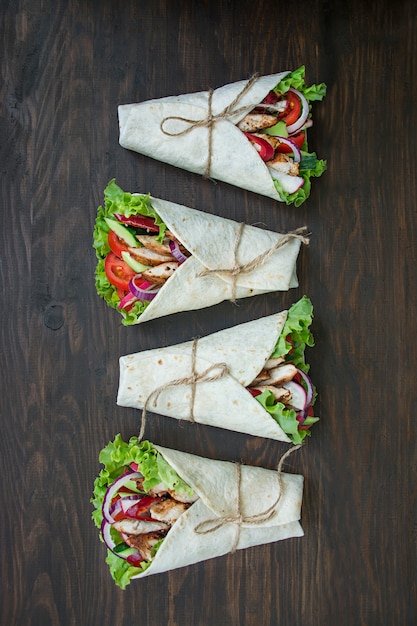 Mexican dish.Taco with chicken and vegetables close-up on a wooden surface. 