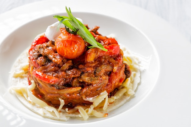 Mexican food beef fajitas with peppers and pasta on white plate