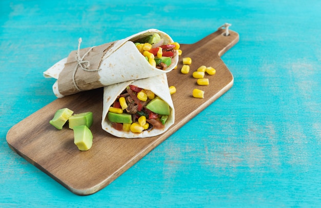 Mexican food. Burritos on kitchen table on blue background. Mexican cuisine concept. Copy space.