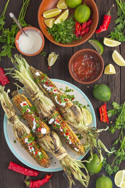 Mexican grilled corn with hot chili sauce on the dining table, top view