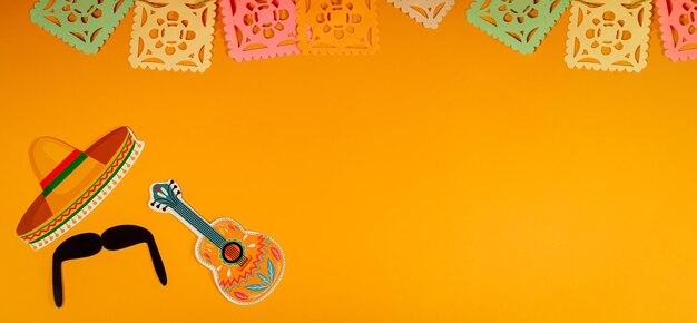 Photo mexican holiday background paper garlands decorating guitar and hat on orange background