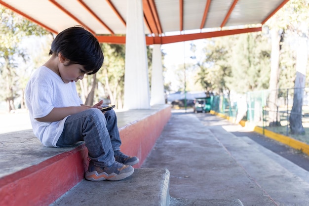 Mexican kid playing with Mobile Devices outdoors