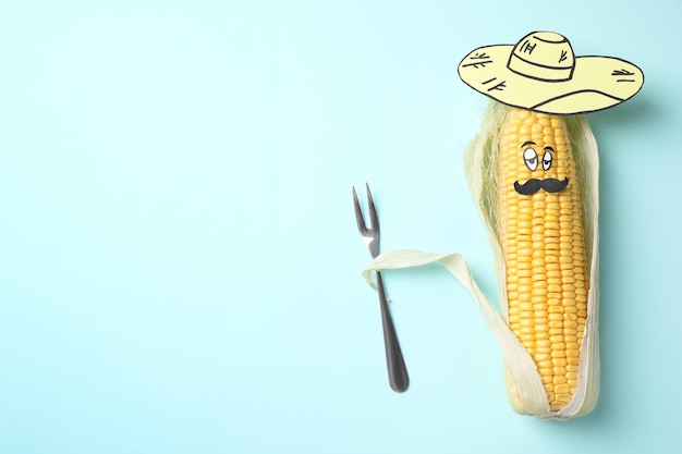 Mexican man of corncob paper hat and fork on light blue background top view Space for text