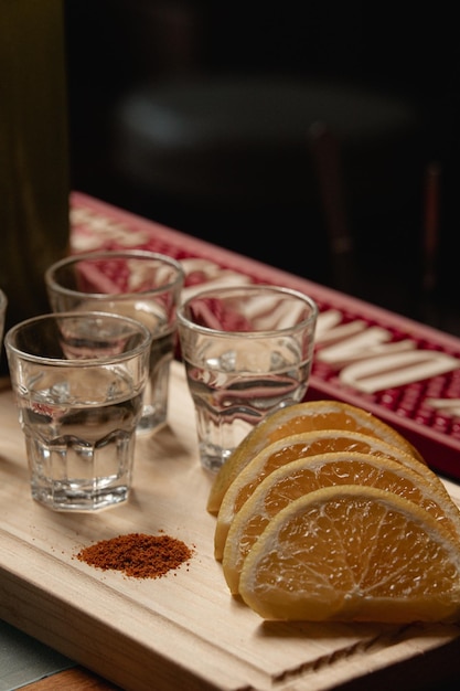 mexican mezcal shots on wooden board with chili and orange slices