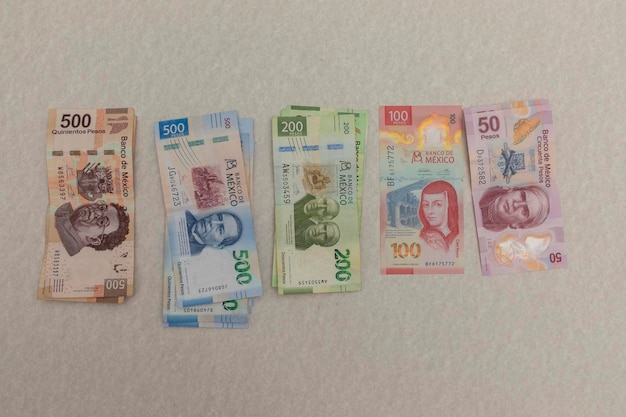 Mexican peso bills arranged by denomination on a marble surface