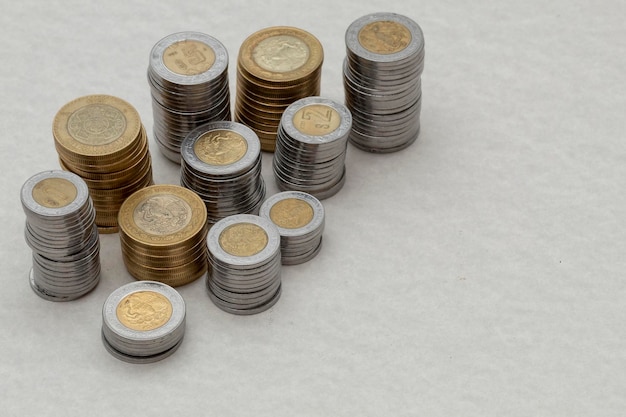 Mexican peso coins of different denominations stacked on a table with copy space