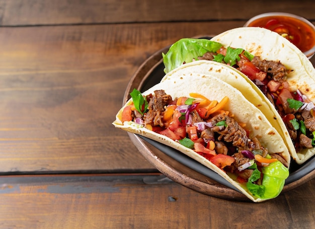 Mexican Tacos With Beef In Tomate And Salad On Wooden Table