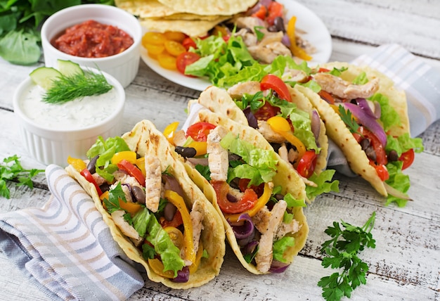 Mexican tacos with chicken, bell peppers, black beans and fresh vegetables