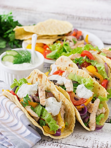 Mexican tacos with chicken, bell peppers, black beans and fresh vegetables