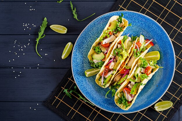 Photo mexican tacos with chicken meat, avocado, tomato, cucumber and red onion.