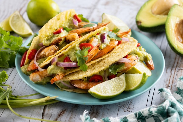 Mexican tacos with shrimpguacamole and vegetables on wooden table