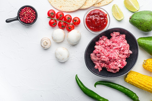 Mexican tacos with vegetables and meat. Ingredient for cooking, corn, meat Top view over white background with space for text.