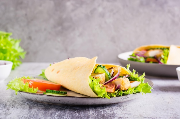 Mexican tortilla wraps with vegetables and chicken on a plate on the table