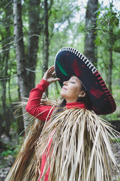 Mexican woman wearing a mariachi hat and capisayo or cape made of palm leaves