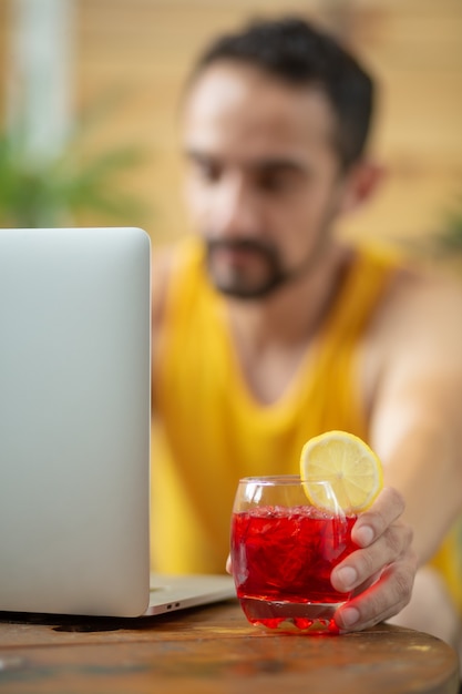 Mexican young man working on summer vacation drinking a cocktail vertical