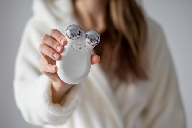 Microcurrent device for massage of a woman's face in her hands selective focus closeup