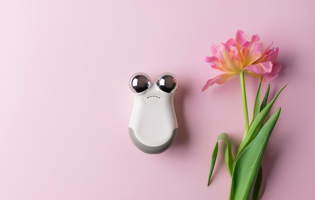 Microcurrent facial toning device on color background with flower