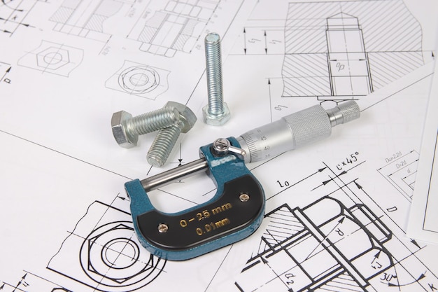 Micrometer and bolts on a background of engineering drawings Science mechanics and mechanical engineering