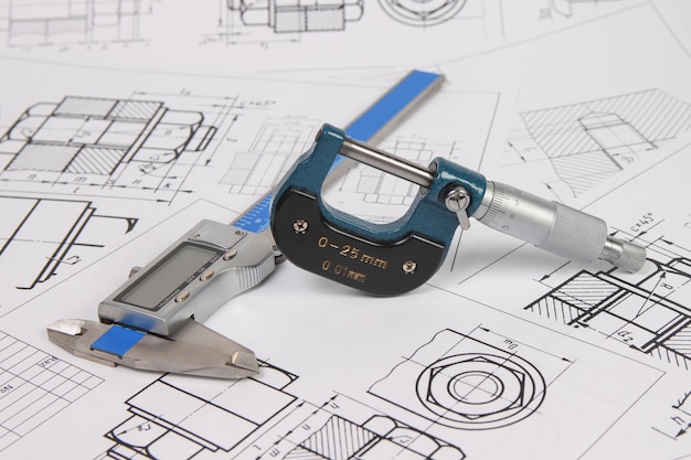 Micrometer and caliper on a background of engineering drawings Science mechanics and mechanical engineering