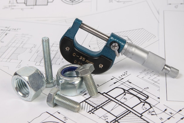 Micrometer and hardware on a background of engineering drawings Science mechanics and mechanical engineering