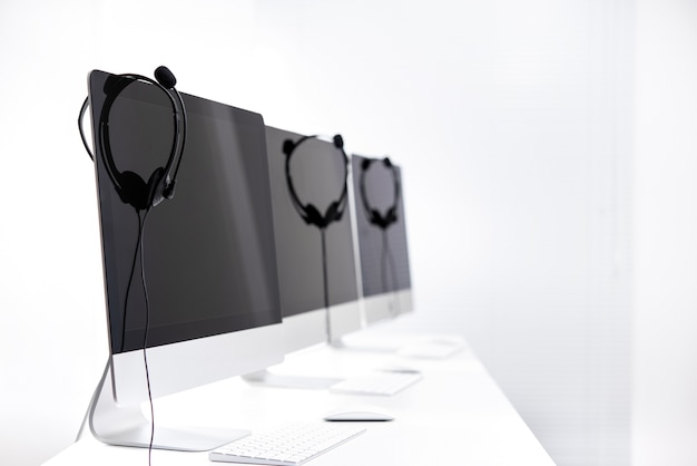 Microphone headsets hanging on computer monitors 