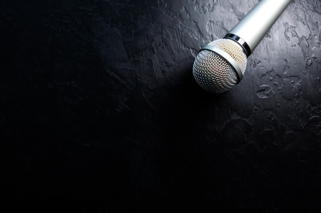 Photo microphone lying on the black background. free time activities at home. karaoke hobby. music concept.